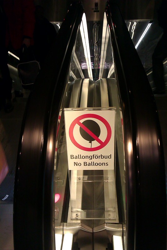 A sign near the escalators at a Danish railway station saying (in English and Danish): No Balloons.
