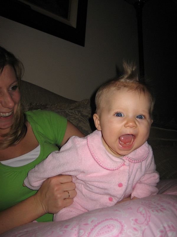 A very enthusiastic toddler being held by a smiling adult