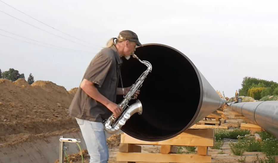 man playing a saxophone into a pipeline