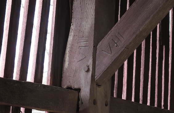 Part of a timber framed building, with two pieces of wood meeting at a joint. The number VIII is written on both bits of wood.