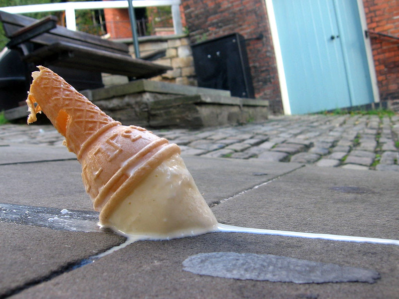An ice cream cone that has been dropped onto the pavement